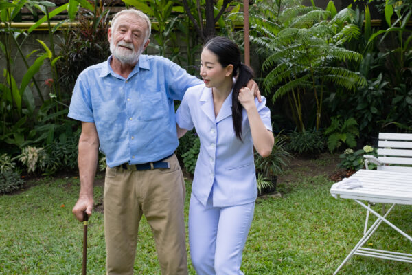 Caregiver providing transfer assistance to a senior man with Parkinson's disease in Raleigh North Carolina